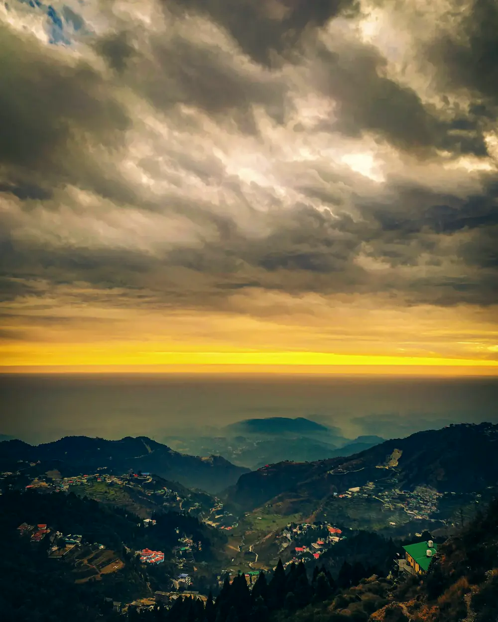 Storm clouds breaking over a gold horizon above the hills of Mussoorie, the Doon valley below.